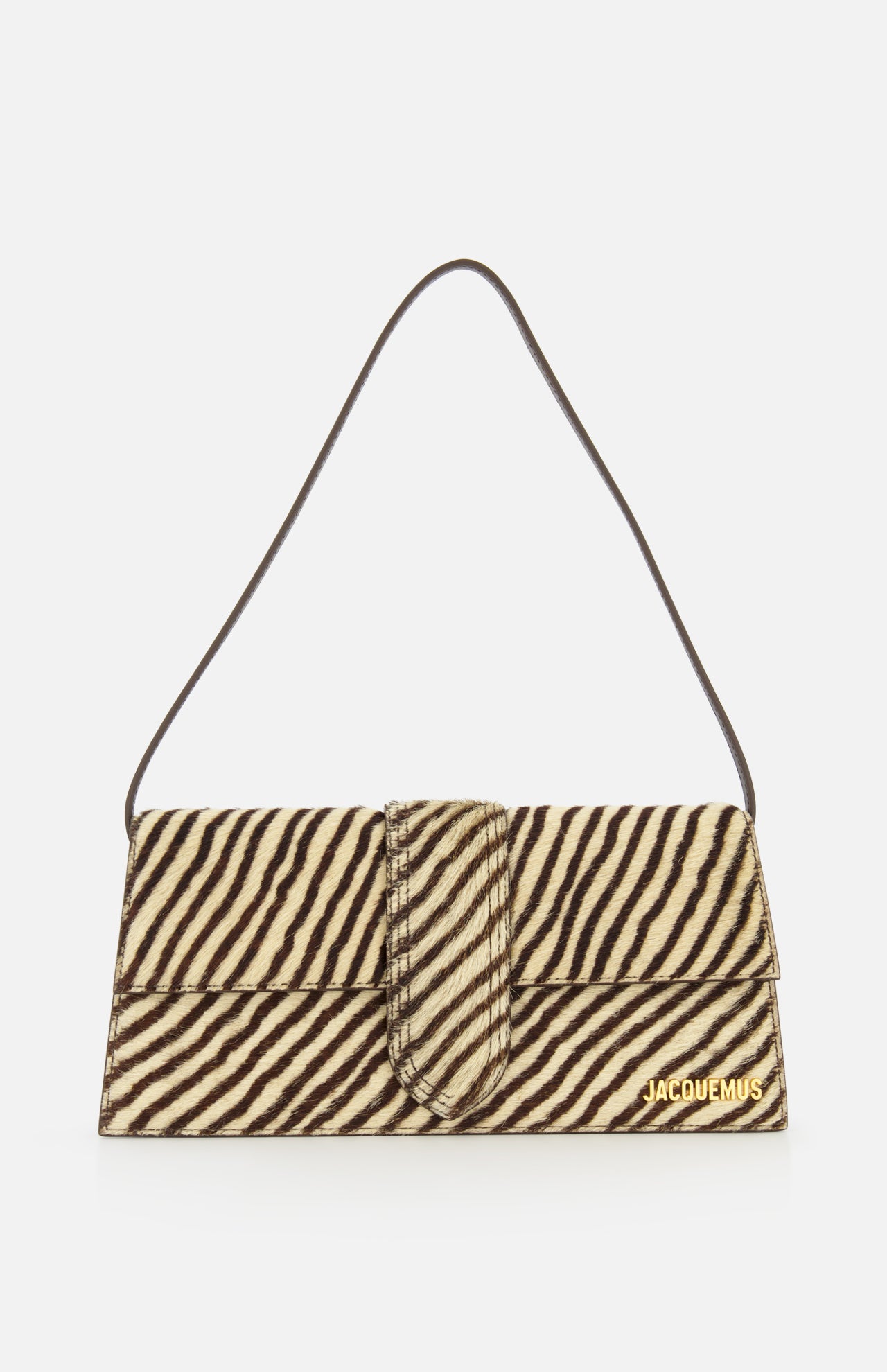 The Le Bambino Long Zebra Shoulder Bag by JACQUEMUS is a rectangular, zebra-print calf hair accessory featuring a short strap and gold JACQUEMUS branding in the lower right corner. Made in Italy, it is shown against a white background.