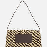 The JACQUEMUS Le Bambino Long Zebra Shoulder Bag is a rectangular animal print accessory showcasing a bold zebra stripe pattern, a dark rectangular front patch, and a slim dark shoulder strap, all displayed against a plain white background.