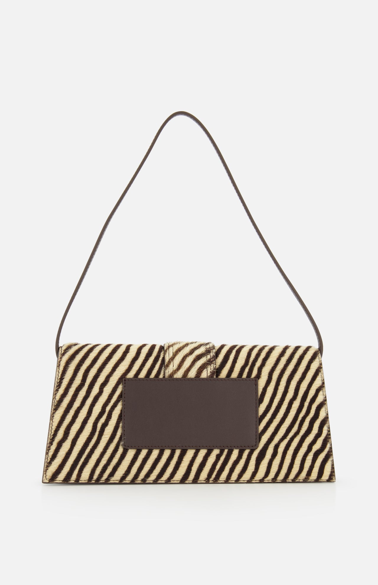 The JACQUEMUS Le Bambino Long Zebra Shoulder Bag is a rectangular animal print accessory showcasing a bold zebra stripe pattern, a dark rectangular front patch, and a slim dark shoulder strap, all displayed against a plain white background.