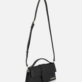 The Le Grand Bambino Bag by JACQUEMUS is a sleek black leather top-handle bag with an adjustable crossbody strap, flap closure, and the Jacquemus logo in small white letters on the front lower corner. Made in Italy.