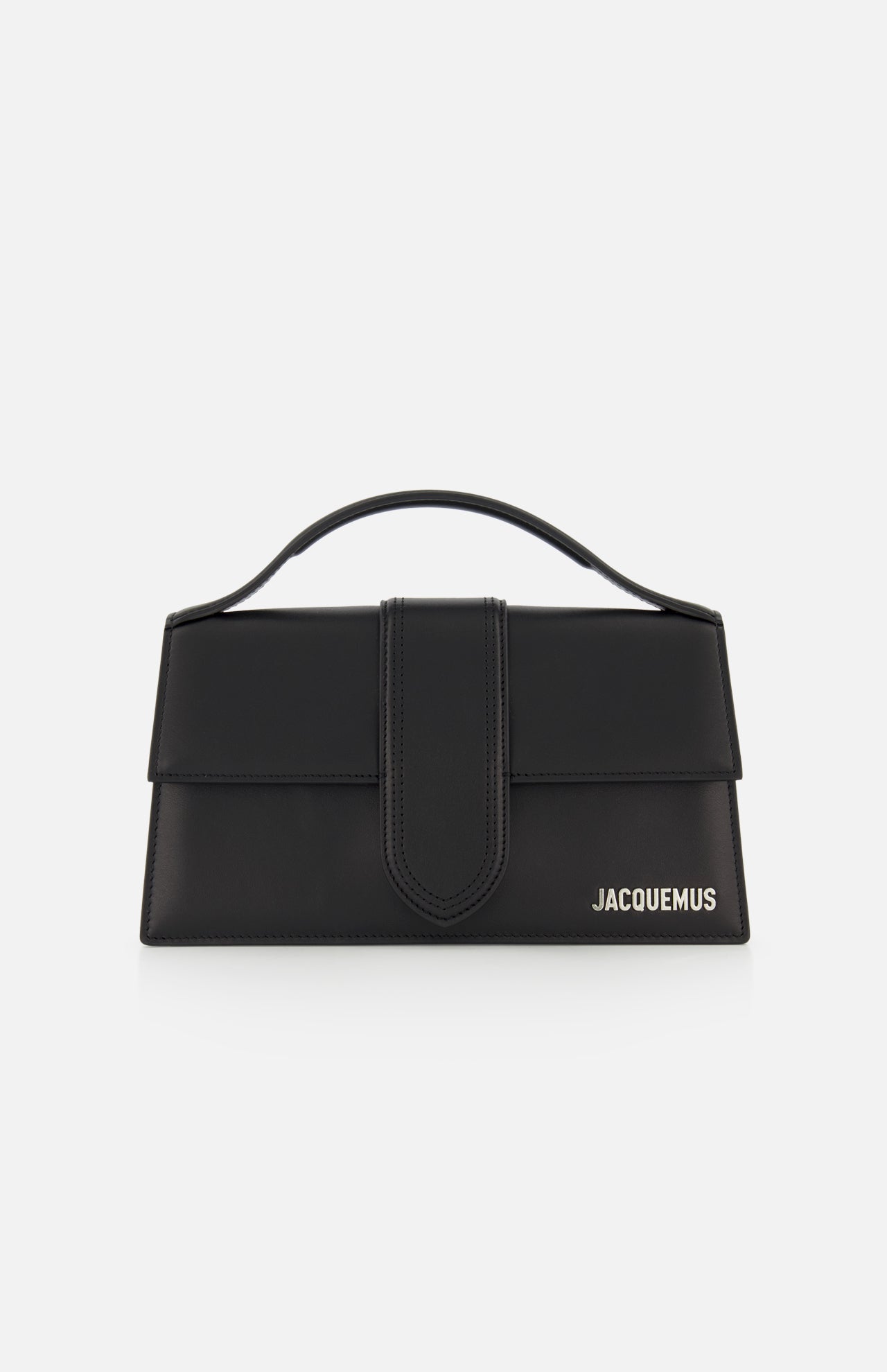 The Le Grand Bambino Bag by JACQUEMUS is a black leather top-handle bag with a flap closure, adjustable crossbody strap, and the JACQUEMUS logo in white on the lower right—made in Italy and shown against a white background.