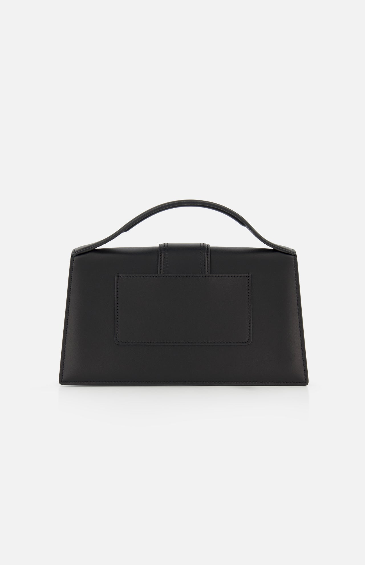 The JACQUEMUS Le Grand Bambino Bag is a minimalist black leather rectangular top-handle bag made in Italy, shown against a plain white background.