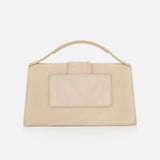 The Le Grand Bambino Bag by JACQUEMUS is a rectangular beige suede tan leather top-handle bag with a large front pocket and short handle, shown against a plain white background.