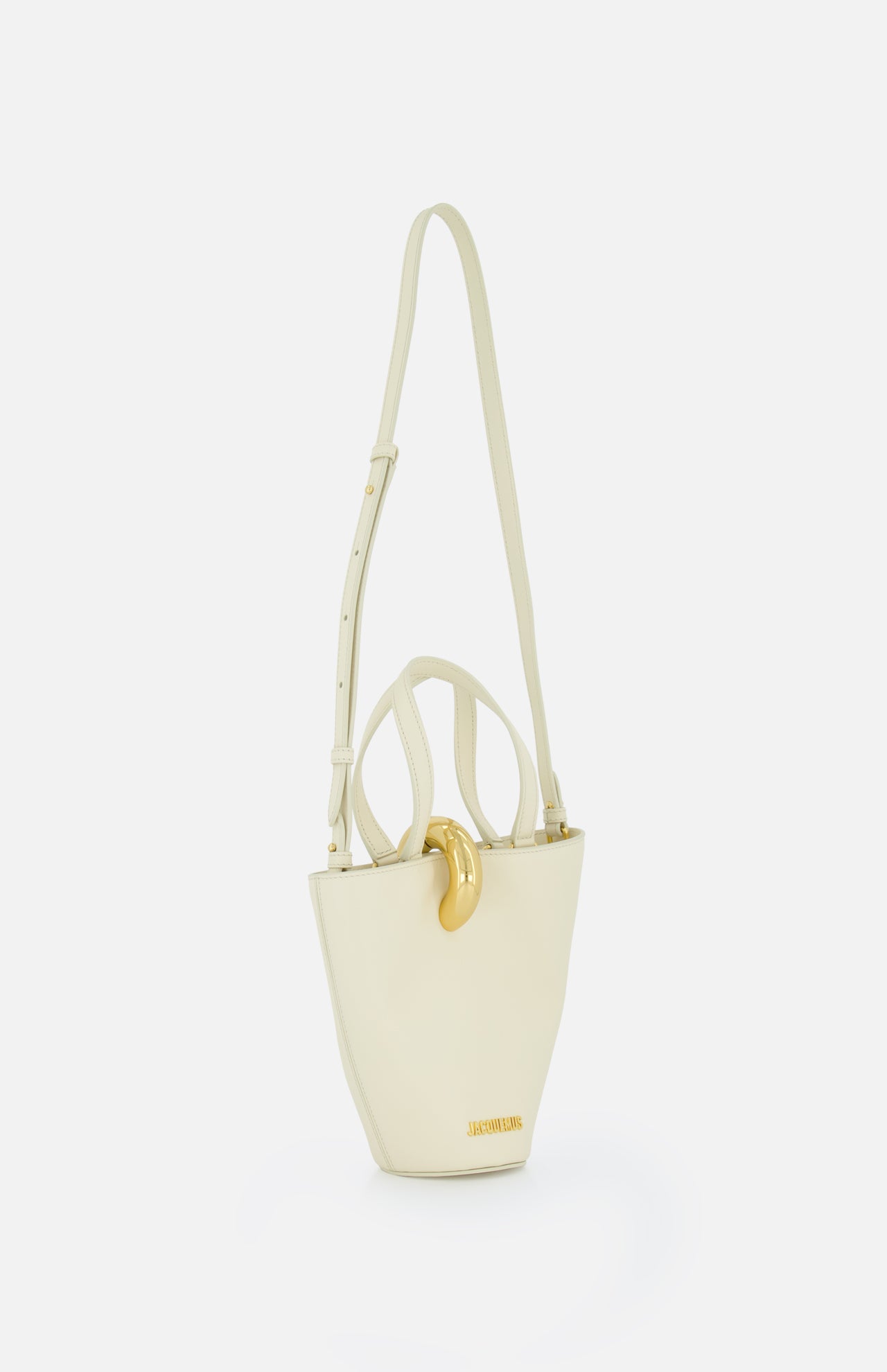 The JACQUEMUS Le Petit Bambola Tote Bag is an ivory leather bucket bag with a structured shape, gold hardware, an adjustable shoulder strap, front gold accent, and JACQUEMUS branding—bringing elegance to any look.