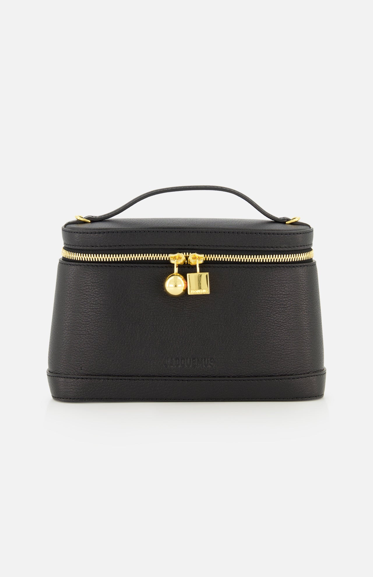 The Le Petit Vanity Bag by JACQUEMUS is a black leather bag with a structured silhouette, featuring a top handle, gold zipper, and gold lock details reminiscent of a vintage vanity case. It is displayed against a plain white background.