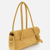 The Le Turismo Long Shoulder Bag by JACQUEMUS is a medium-sized, mustard yellow suede handbag featuring a textured grid-like pattern, long rounded handles, and a distinctive knotted detail on one side. Expertly crafted in Italy, this elegant accessory is showcased against a plain white background.