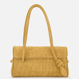 The Le Turismo Long Shoulder Bag by JACQUEMUS—a tan croc-effect suede handbag in a mustard yellow hue, crafted in Italy with a textured crocodile-style pattern, sophisticated flap closure, and a single knotted shoulder strap—is elegantly displayed on a white background.