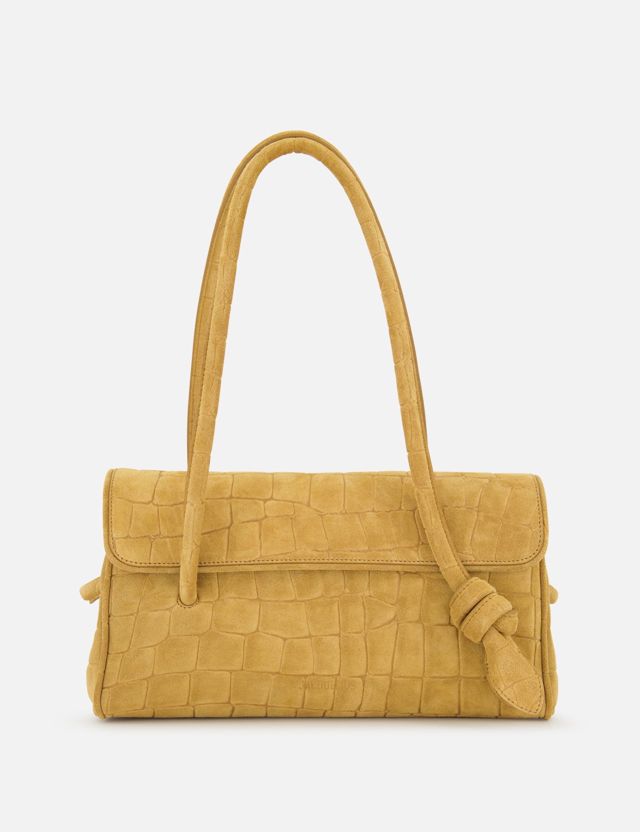 The Le Turismo Long Shoulder Bag by JACQUEMUS—a tan croc-effect suede handbag in a mustard yellow hue, crafted in Italy with a textured crocodile-style pattern, sophisticated flap closure, and a single knotted shoulder strap—is elegantly displayed on a white background.