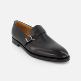The JOHN LOBB Delano II Oxford Loafer is a single black leather dress shoe with a low heel, sleek buckle detail, and smooth polished finish, showcased on a plain white background.
