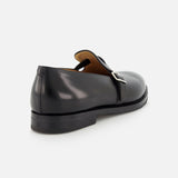 The JOHN LOBB Delano II Oxford Loafer in black leather features a single silver buckle, smooth finish, and low heel, shown from the back and side against a light background.
