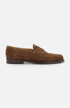 The JOHN LOBB Lopez Suede Loafer is a handmade dark brown suede shoe with white stitching, a low matching heel, and classic penny slot detail, crafted in England and shown on a plain white background for timeless style.