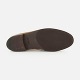 The image displays the bottom view of the JOHN LOBB Bath Nubuck Loafer, highlighting its dark brown sole and heel. Small gold-colored nails are visible near the heel, with imprinted text located near the center. The product is photographed against a white background.