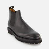 The JOHN LOBB Lawry Calfskin Boot is displayed on a plain white background. This single black boot showcases a classic Chelsea slip-on style with elastic side panels, a pull tab at the back, and a thick, ridged sole.