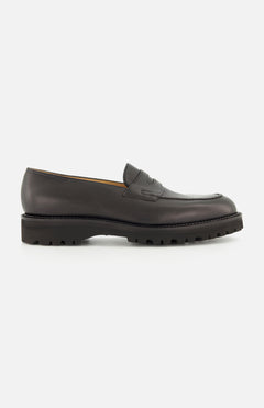 The Lopez Gentle Grain Loafer by JOHN LOBB is displayed in a side profile view against a plain white background, showcasing the expert craftsmanship of these handmade dark brown leather shoes with a chunky, ridged black sole, made in England.