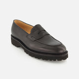 The Lopez Gentle Grain Loafer by JOHN LOBB is expertly crafted in England from black leather, featuring a chunky textured sole, visible stitching, and a classic penny slot detail on the upper—shown against a plain white background.