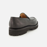 Lopez Gentle Grain Loafer by JOHN LOBB in black gentle grain leather, handmade in England, featuring a chunky treaded sole, shown from the back on a white background.
