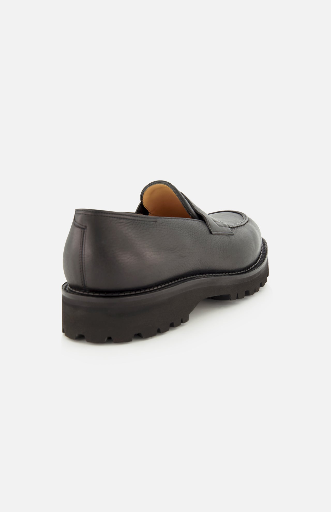Lopez Gentle Grain Loafer by JOHN LOBB in black gentle grain leather, handmade in England, featuring a chunky treaded sole, shown from the back on a white background.