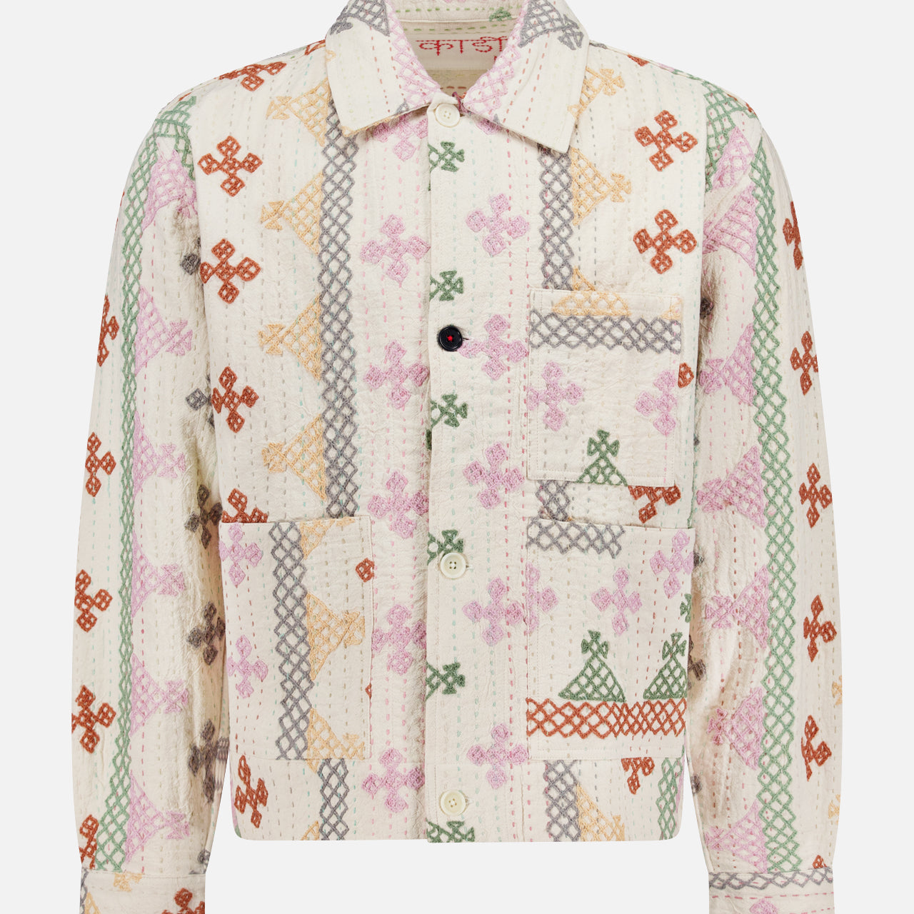 The KARDO Bodhi Shirt Jacket is a long-sleeve, collared jacket made in India from 100% cotton. It features a front pocket, quilted texture, and multicolored floral and geometric patchwork on a white background.