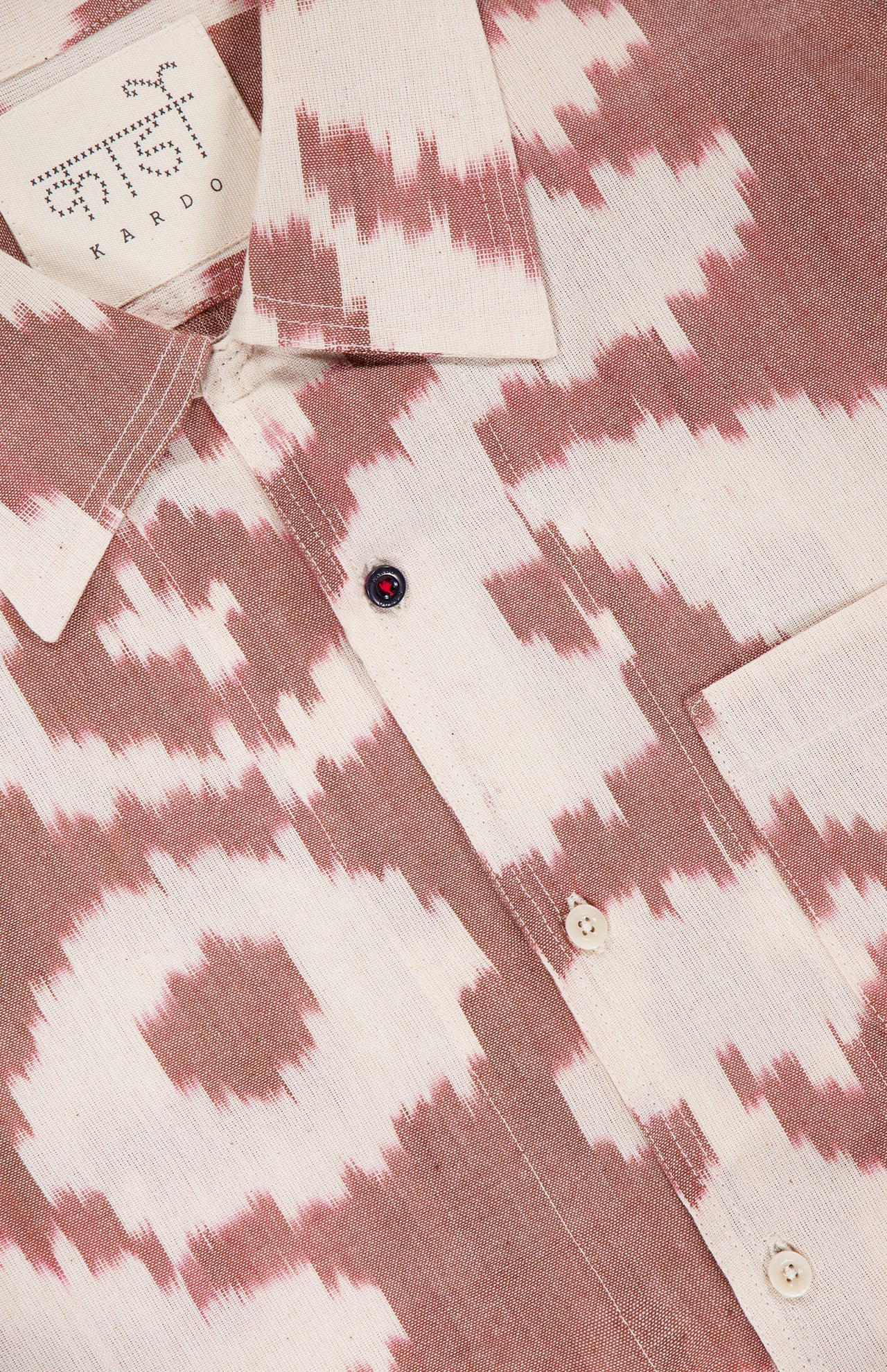 Close-up of the KARDO Chintan Short Sleeve Shirt, 100% cotton with a pink and white abstract ikat-style pattern, cream buttons, and a branded "KARDO" label.