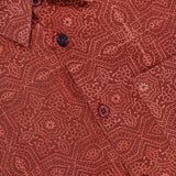 A close-up of the KARDO Luis Oversized Long Sleeve Shirt in brick red showcases its intricate geometric and floral pattern, with buttons visible along the placket.