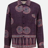 The Martin Relaxed Fit Long Sleeve Shirt from KARDO is a printed, relaxed-fit button-up featuring a purple base with blue and red circular and dotted patterns, highlighted by decorative border designs along the hem, cuffs, and lower sleeves.