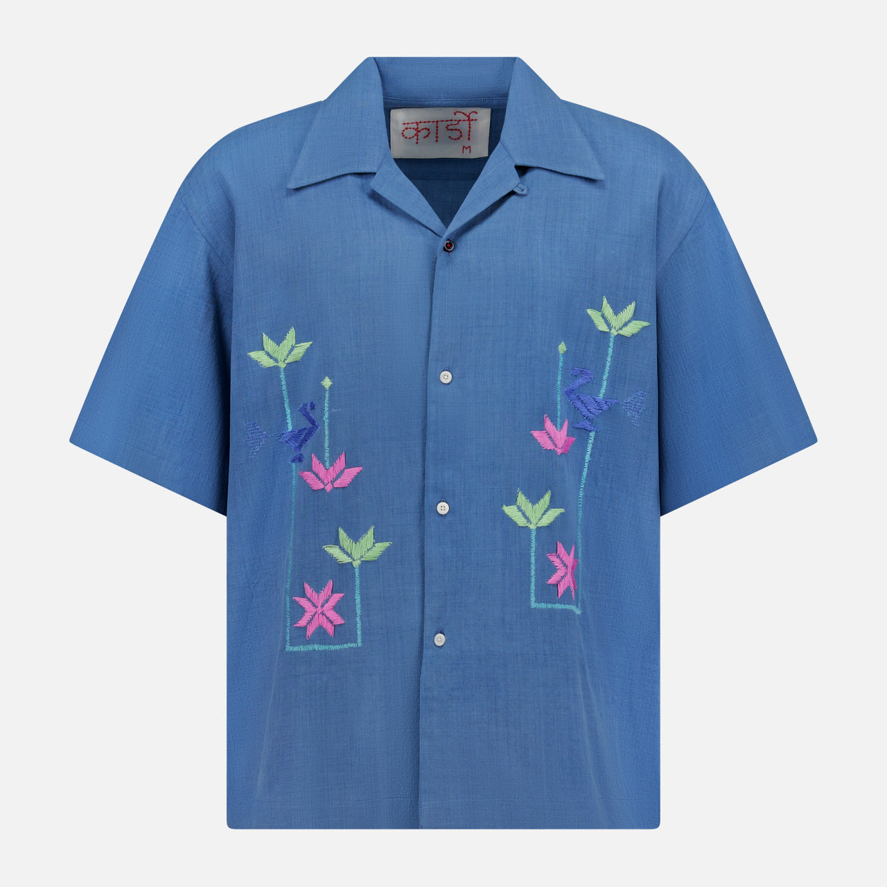 The KARDO Rohit Short Sleeve Embroidered Shirt features an oversized fit, blue color, collar, and vibrant pink, green, and purple floral and bird embroidery on the front.