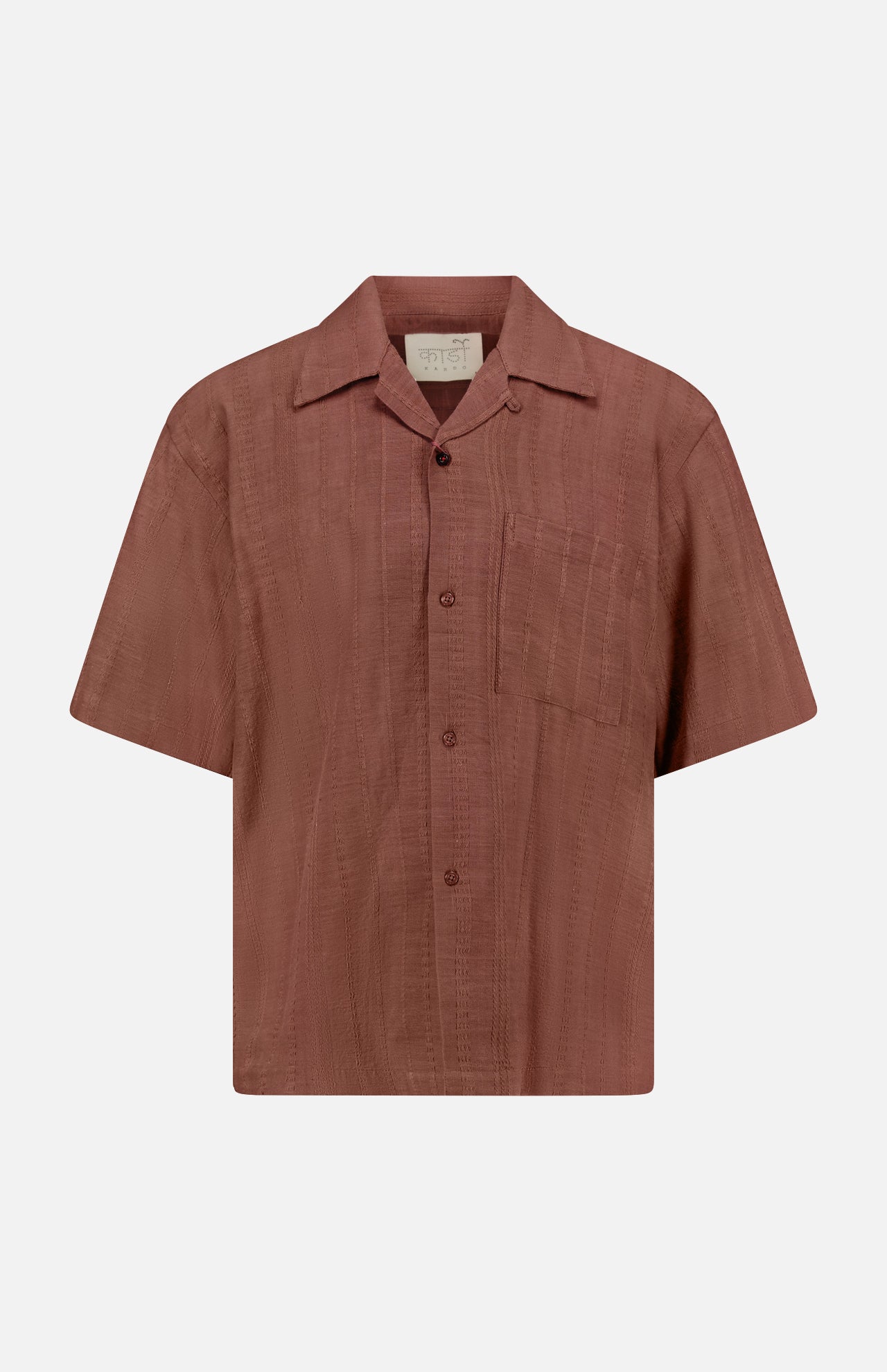 The KARDO Rohit Stripe Short Sleeve Shirt is a brown, 100% cotton, oversized button-up with a chest pocket, collar, and subtle textured stripes. Displayed on a plain white background.