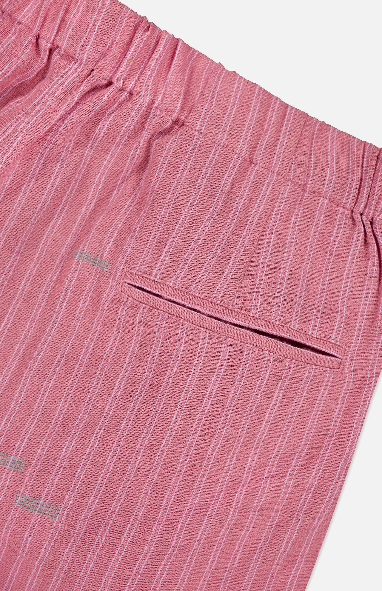 Close-up of KARDO's Taka Striped Trouser Pants—women's relaxed fit in pink with thin white vertical stripes, an elastic waistband, and a single welt back pocket.