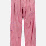 The KARDO Taka Striped Trouser Pants are relaxed-fit, high-waisted cotton pants with front pleats, button closure, subtle white stripes, and purple embroidered accents.
