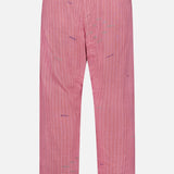 Back view of KARDO's Taka Striped Trouser Pants featuring pink fabric with thin vertical white stripes, subtle purple stitching, an elastic waistband, and two welt pockets at the upper back.