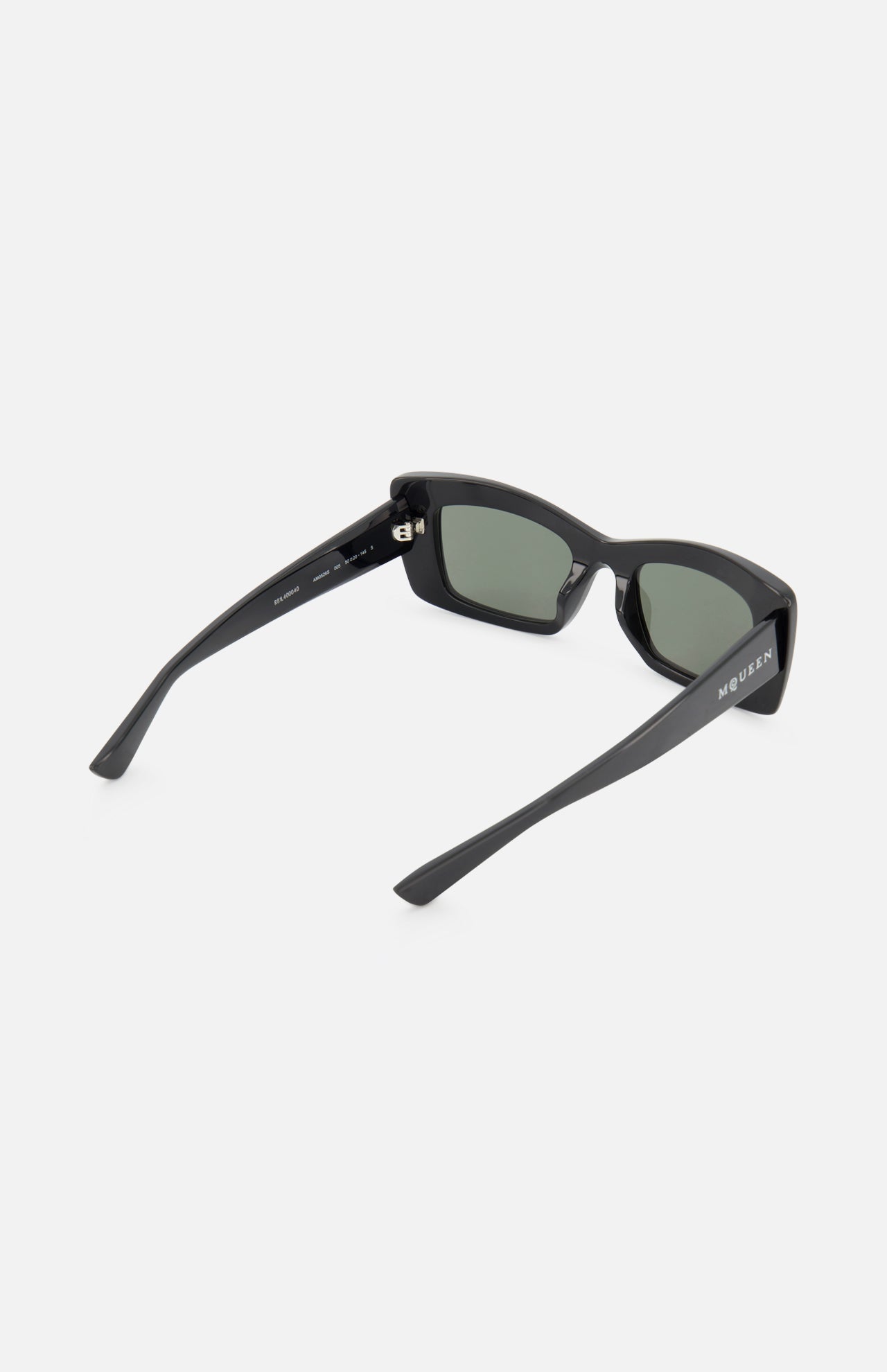 Alexander McQueen Cat Eye Black Sunglasses by ALEXANDER MCQUEEN, shown at an angle highlighting the left side and back. The black frame has dark lenses and one arm is engraved with “Moulin” in white. Set against a plain white background.