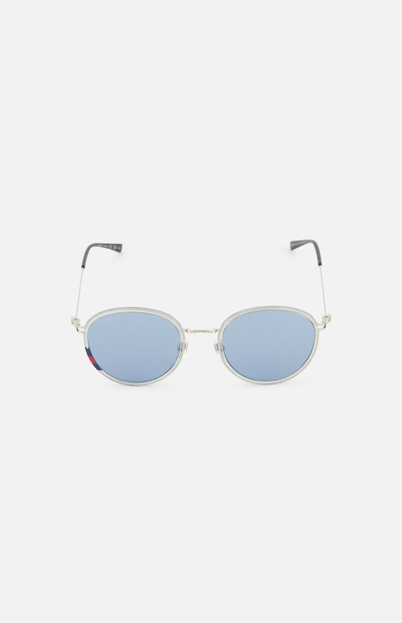 The Gucci Round Silver Sunglasses by GUCCI feature silver metal round frames, light blue tinted lenses, and black-tipped arms. These unisex sunglasses are displayed on a plain white background.