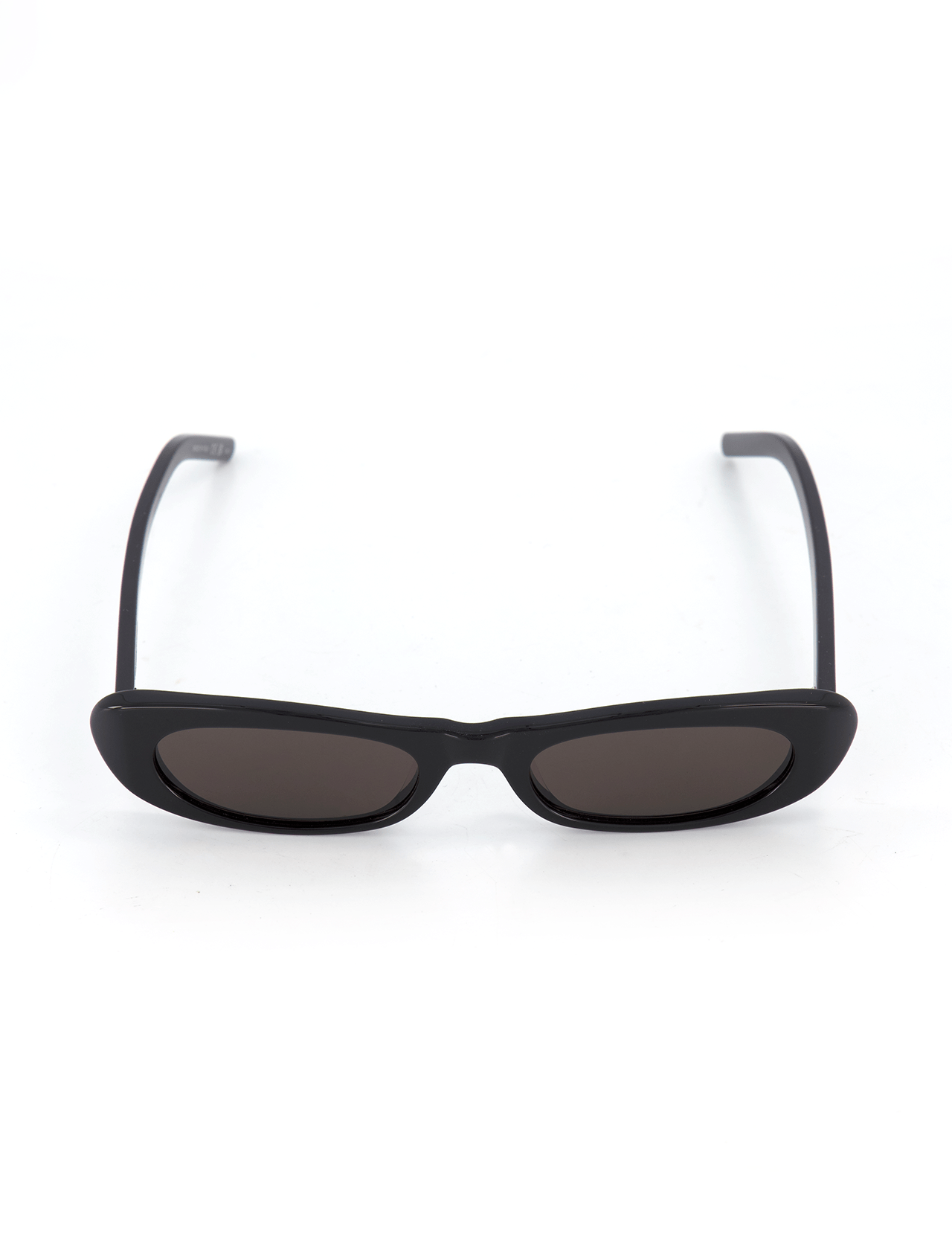 The YVES SAINT LAURENT Shade Oval Frame Sunglasses feature a minimalist black oval frame, narrow rectangular dark lenses, and slightly curved acetate arms, shown against a white background.
