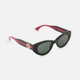 GUCCI Cat Eye Black Sunglasses with green lenses, red and black arms, gold Gucci logo on the temple, and red interior arms are displayed on a white background.
