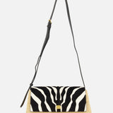 The KHAITE Audrey Raffia Crossbody Bag features a woven straw base, black adjustable strap, and a striking black and white animal print flap for standout style.