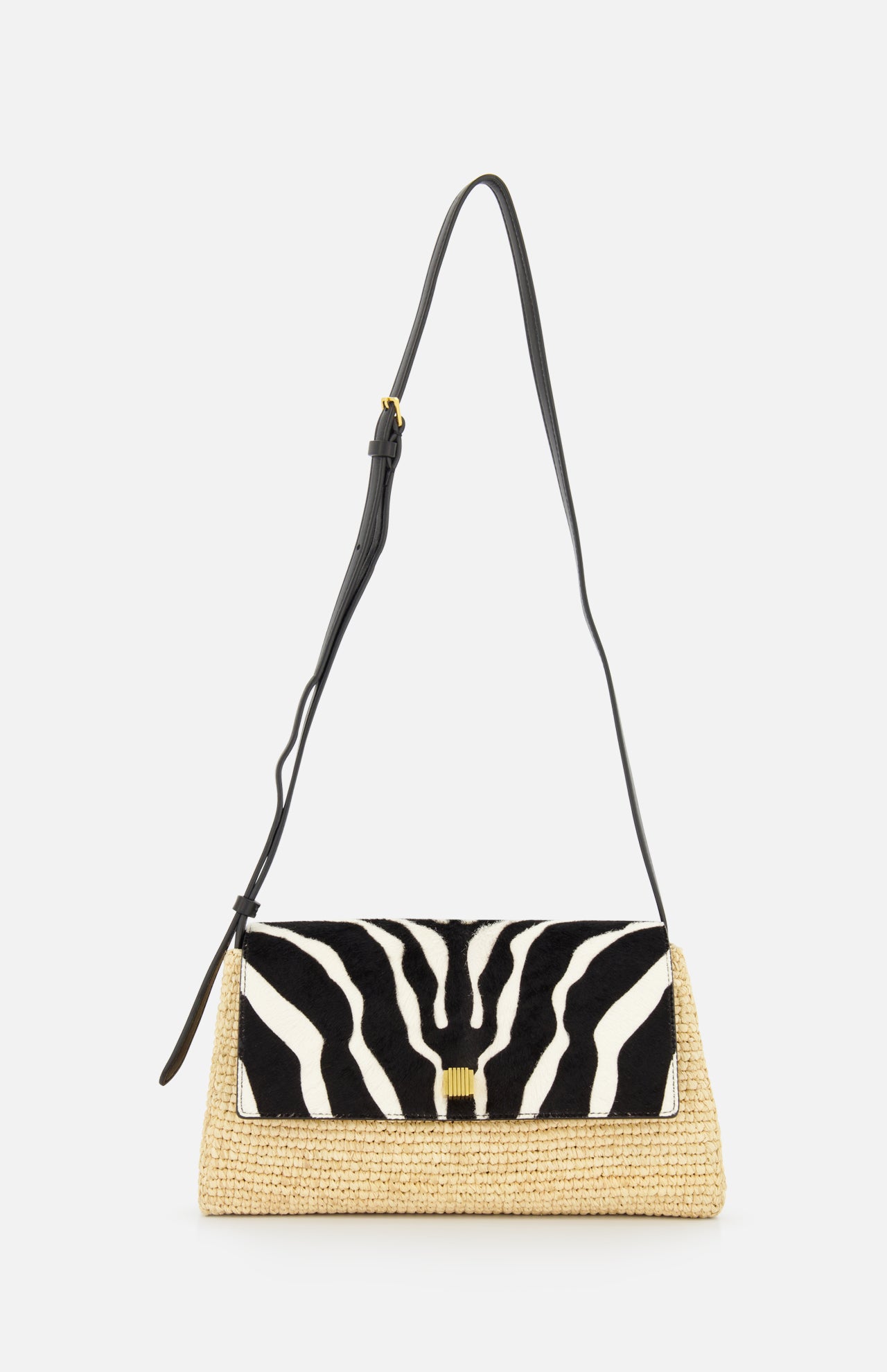 The KHAITE Audrey Raffia Crossbody Bag features a woven straw base, black adjustable strap, and a striking black and white animal print flap for standout style.