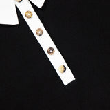Close-up of the KHAITE Faithful Vintage Rugby Top, a black unisex silk polo shirt with a white collar and four marbled buttons on its white placket. The inner collar label displays "KHAITE.