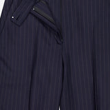 A close-up of KHAITE's Jude Striped Wool-blend Pant in navy, highlighting its pinstripes, front fly with button and zipper closure, and button-tab waistband—ideal for a timeless, minimalist look.