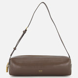 The KHAITE Kye Patent Leather Shoulder Bag features brown patent leather, a cylindrical shape, adjustable strap, gold zipper, and a small gold logo at the front center. It is shown against a white background.