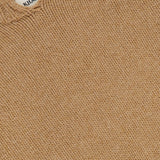 Close-up of the beige Cain Split Neck Cashmere Sweater by KHAITE, showcasing its textured stitching and a small white label near the neckline—a luxurious Italian cashmere choice for any minimalist wardrobe.