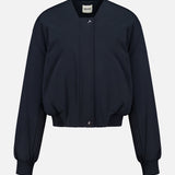 The Cordan Cropped Bomber Jacket by KHAITE is showcased against a plain white background, featuring a navy blue hue, long sleeves, ribbed cuffs and hem, and a front snap button closure—an ideal addition to any minimalist wardrobe.
