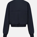 Back view of the KHAITE Cordan Cropped Bomber Jacket in dark navy blue nylon, featuring ribbed cuffs and waistband, displayed against a white background—a sleek option for a minimalist wardrobe.