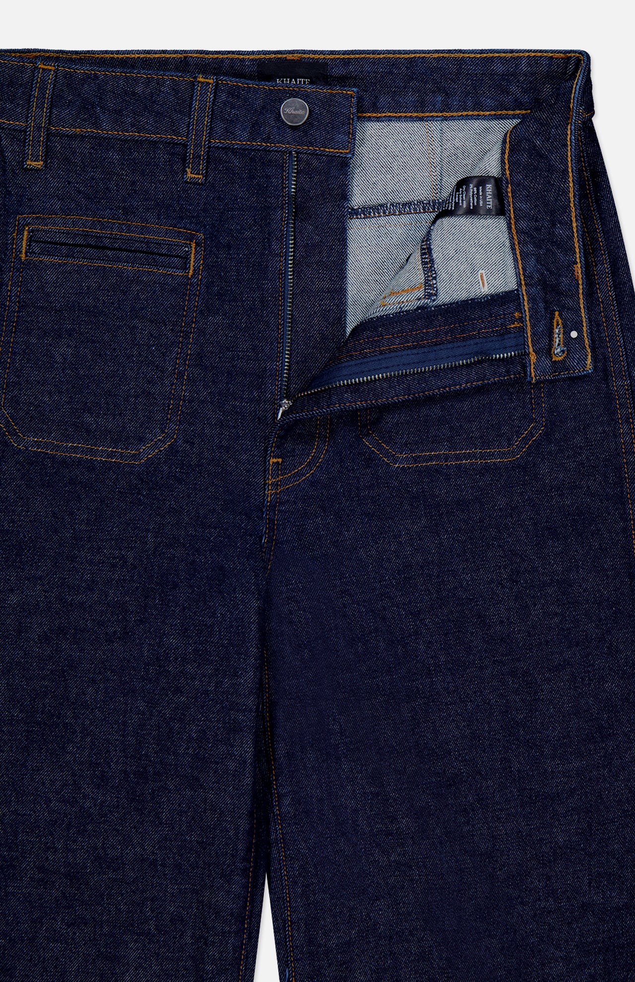 The KHAITE Delmonico Wide Leg Jean in Benson, a dark wash high-waisted style with orange stitching, is shown laid flat from above and partially unzipped to display the inside waistband and pocket details.