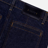 Close-up of the back pocket and waistband of the KHAITE Delmonico Wide Leg Jean in Benson, featuring a high-waisted, dark wash design with yellow stitching and a black leather patch stamped with the brand name in gold letters.