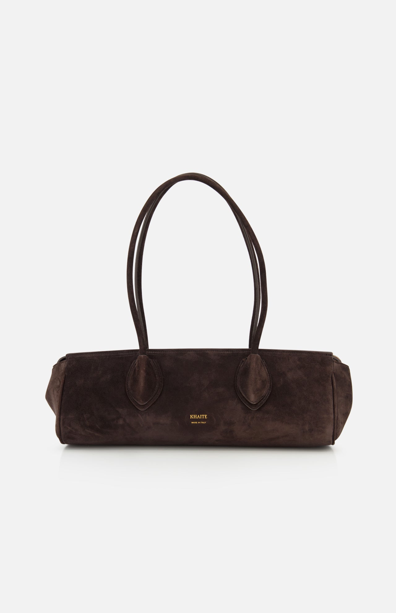 The Donna Soft Handbag by KHAITE is expertly crafted in Italy from dark brown suede. It features two long shoulder straps, rounded handles, and a rectangular silhouette. The front is adorned with the KHAITE brand name printed in small gold lettering.