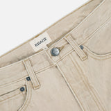 Close-up of the Finley Jean in Dumas by KHAITE, featuring a mid-rise waistband, front pockets, metal button, and inner KHAITE label. Crafted from stretch-free denim with visible stitching and a lightly textured beige finish.