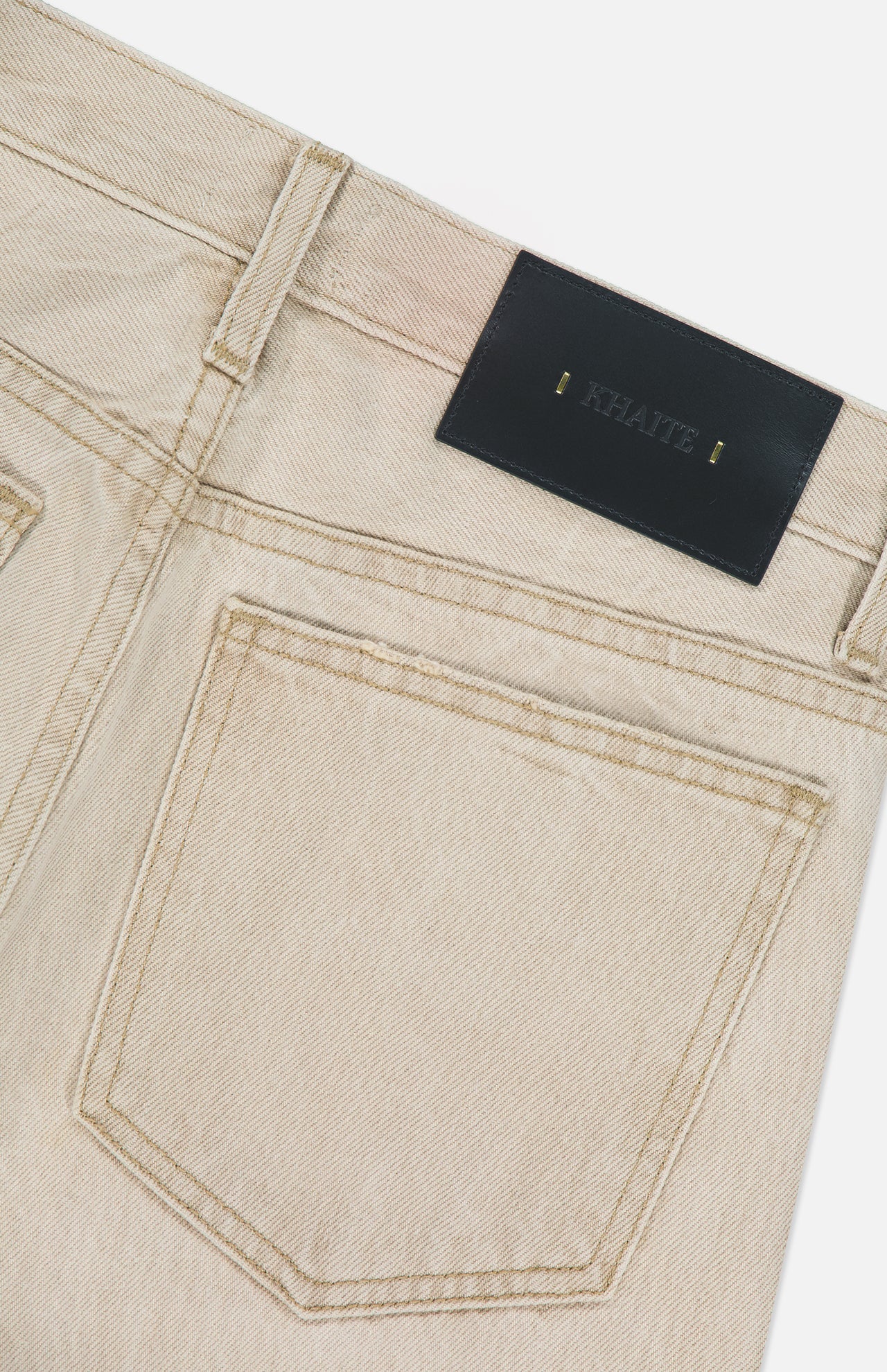 Close-up of the back of the KHAITE Finley Jean in Dumas, featuring visible stitching, a large back pocket, belt loops, and a black leather patch with gold text. Crafted in stretch-free denim with a mid-rise cut for timeless style.