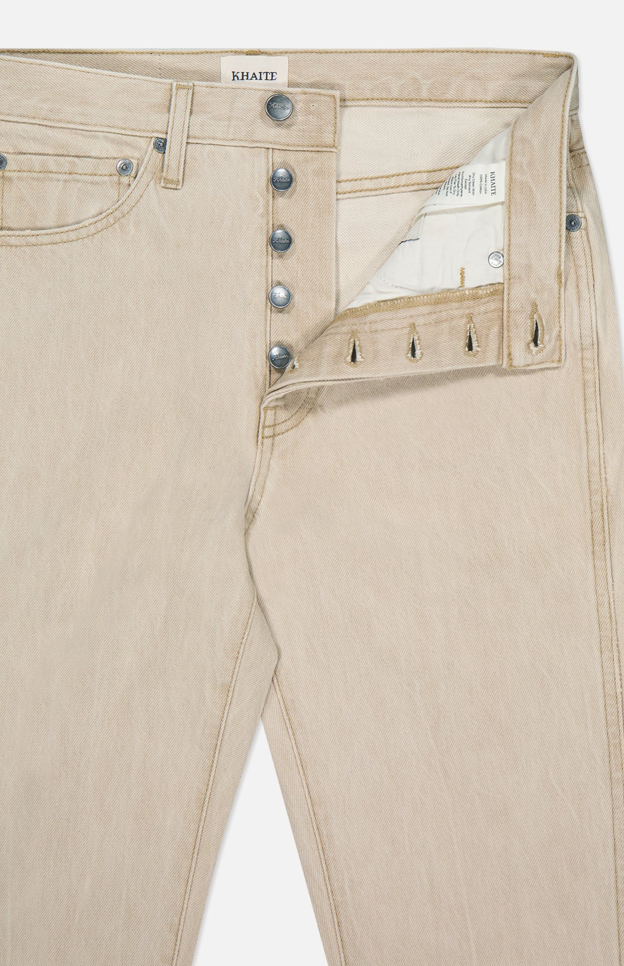 The Finley Jean in Dumas by KHAITE is crafted from stretch-free beige denim, features silver fly buttons, reveals its inside label and pocket lining, and is designed in a classic five-pocket, timeless mid-rise cut.