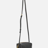 The KHAITE Kye Mini Crossbody Bag is a small black Italian-made bag with sleek leather, a long adjustable strap, gold zipper and charm, minimalistic design, and subtle branding near the bottom.