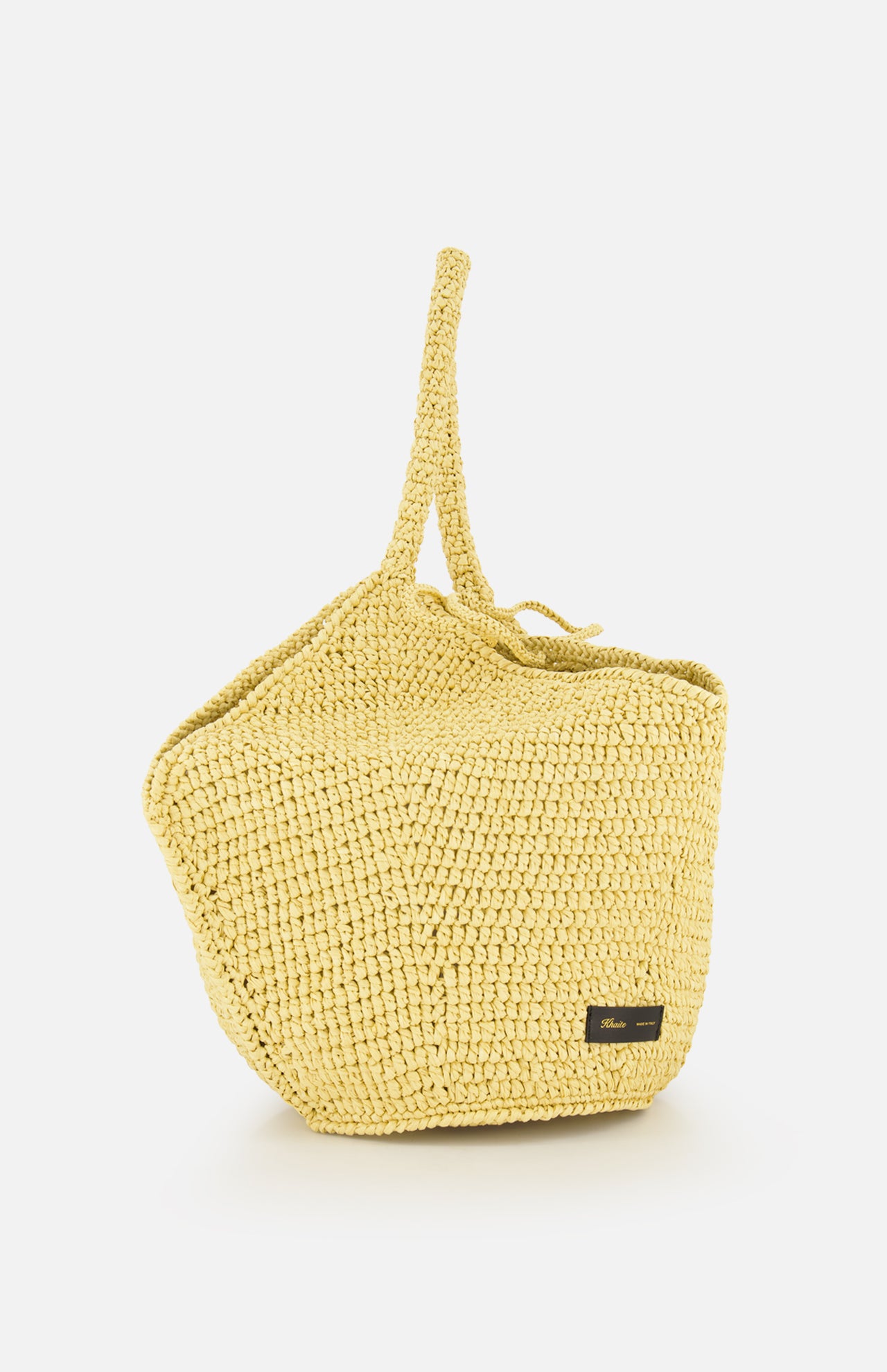 The KHAITE Lotus Viscose Raffia Medium Bag is a yellow Italian straw bag with a single top handle and a small black rectangular label on the front, displayed against a plain white background.